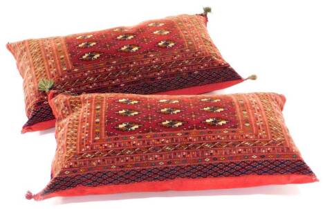 A near pair of large rectangular Belouch carpet cushions, with a design of medallions on a red ground with numerous borders, 105cm x 52cm.