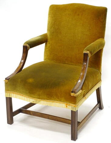 A mahogany open armchair in George III style, upholstered in green velvet on chanelled legs.