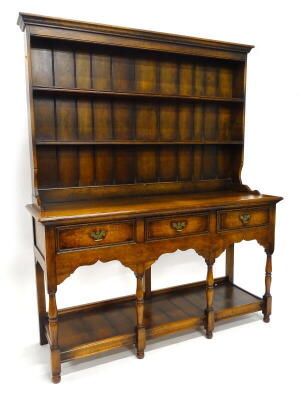 An oak dresser in the late 18thC style, the back with a moulded cornice above two shelves, the base with a moulded edge above three frieze drawers and arched frieze, on turned legs with pot board, 192cm high, 157cm wide, 52cm deep.