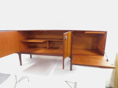 A McIntosh and Co Limited 1960's Rosewood dining suite, comprising a sideboard, with a pair of doors opening to reveal a shaped shelf, flanked to the left by three drawers, the top drawer fitted, to the right by a drop down flap revealing a drinks cabinet - 7