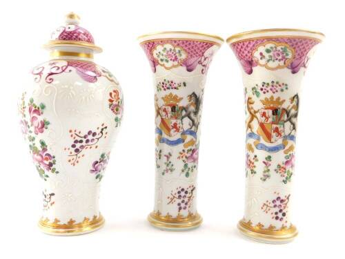 A Samson late 19thC porcelain garniture of vases, decorated in the Chinese export style with armorials and flowers against a scale famille rose ground, comprising a baluster shaped vase and cover, 17.5cm high, and a pair of trumpet shape vases, 15.5cm hig