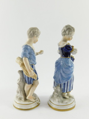 A pair of Unterweissbach 20thC porcelain figures, of a boy and girl, modelled standing with a sheath of corn and basket of grapes respectively, raised on circular bases, printed mark, 21cm high. - 2