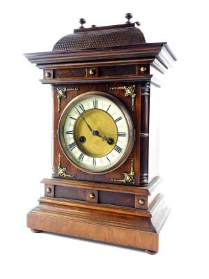 A German late 19thC oak and mahogany cased mantel clock, by the Hamburg American Clock Company, circular brass dial with enamelled chapter ring bearing Roman numerals, eight day movement with coil strike, the case of architectural form, no. 1068, with key