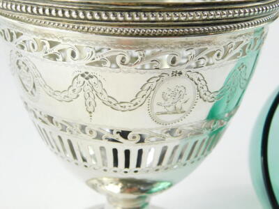 A George III silver sugar basket, with green glass liner, swing handle, pierced and engraved with classical urns, swags and foliate scrolls, oval shield reserve, crest engraved, William Bateman I, London 1820, 5.19oz. - 4