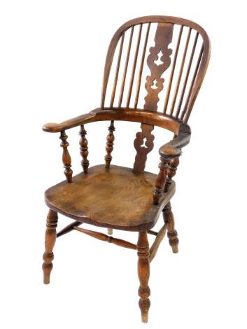 A Victorian oak and elm Windsor chair, with a carved splat and spindle back, solid saddle seat, raised on turned legs united by a double H framed stretcher.