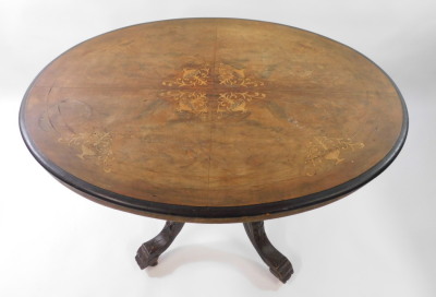 A Victorian walnut and inlaid tilt top loo table, the oval quarter veneered top inlaid with vases of scrolling leaves and line inlay, raised on five turned columns over four leaf carved cabriole legs, on castors, 90cm high, 111cm wide, 86.5cm deep. - 2