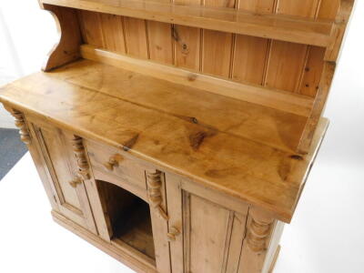 A pine dresser, the two shelf plate rack over a central drawer and recess flanked by cupboard doors raised on a plinth base, 196.5cm high, 133cm wide, 54cm deep. - 3