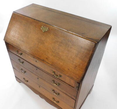 A George III oak bureau, the fall flap opening to reveal a central door, eight recesses and six drawers, over four long graduated drawers raised on bracket feet, 91.5cm high, 99cm wide, 54cm deep. - 4