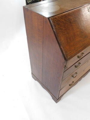 A George III oak bureau, the fall flap opening to reveal a central door, eight recesses and six drawers, over four long graduated drawers raised on bracket feet, 91.5cm high, 99cm wide, 54cm deep. - 6