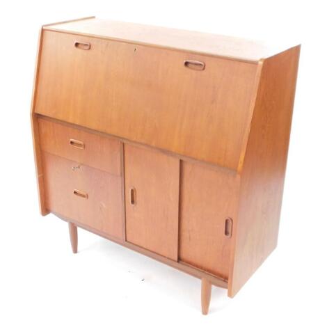 A Burolite teak bureau desk, the fall flap opening to reveal drawers and recesses, over two graduated drawers flanked by a pair of cupboard doors opening to reveal a shelf, raised on turned legs, 103.5cm high, 99cm wide, 41cm deep.