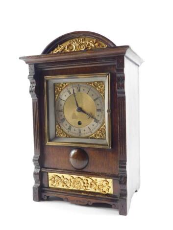 A French early 20thC oak cased mantel clock, square brass dial with foliate spandrels, silver chapter ring bearing Roman numerals, thirty hour movement, No 7024, the case of domed form with gilt floral and foliate embellishments, raised on bracket feet, w