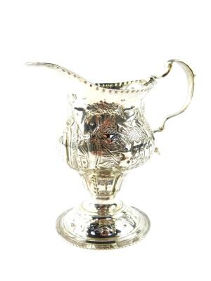 A George III silver cream jug, of ogee baluster form, embossed and engraved with homesteads, rococo shield reserve , monogram engraved, maker TS, London 1819, 2.89oz.