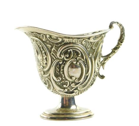 A Victorian silver cream jug, of footed helmet form, with a double scroll handle, embossed with rococo scrolls, shield reserves, Dekin & Francis Ltd, Birmingham 1892, 2.17oz.