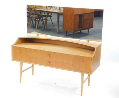 A Meredew mid-century vintage light oak dressing table, the tilting adjustable rectangular mirror over two long drawers, flanked by a pair of deep drawers, raised on tapering square legs united by stretchers, 120cm high, 129cm wide, 46cm deep.