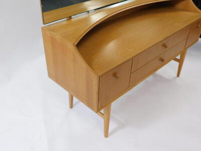 A Meredew mid-century vintage light oak dressing table, the tilting adjustable rectangular mirror over two long drawers, flanked by a pair of deep drawers, raised on tapering square legs united by stretchers, 120cm high, 129cm wide, 46cm deep. - 3