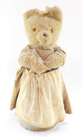 A Reuge musical Teddy bear, wearing a dress and apron, playing rock - a - bye - baby, 36cm high.