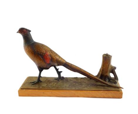 An early 20thC cold painted spelter strike lighter, modelled as a pheasant on a naturalistic ground, and wooden base, 20.5cm high, 31cm wide.