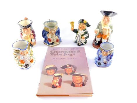 A Royal Doulton pottery character jugs, 19thC and later, comprising of three Toby jugs, a Roy Kirkham Town Crier jug, Royal Doulton Happy John jug and a Jolly Toby jug, together with a book, Desmond Eyles:Royal Doulton character and Toby jugs. (7)