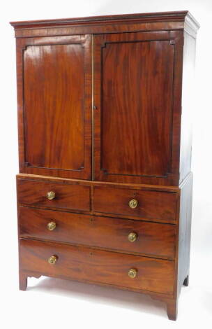 A George IV mahogany linen press, with ebony line inlay and cross banding, the outswept pediment over a pair of panelled doors, opening to reveal four sliding shelves, above two short over two long drawers, on bracket feet, 202cm high, 124cm wide, 59cm de