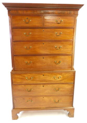 A George III mahogany chest on chest, the outswept pediment with dentil moulding over two short above three long graduated drawers, over three further long graduated drawers, raised on bracket feet, 190cm high, 114cm wide, 56cm deep.