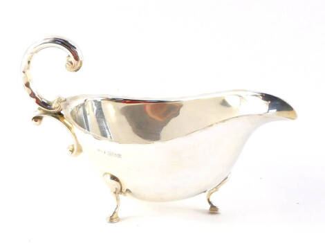 A silver sauce boat, with double C scroll handle, raised on three hoof feet, Birmingham 1970, 3.36oz.