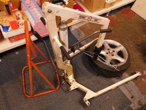 An Oxford Mini 125 hydraulic hoist, together with a Champion equipment stand, and an alloy wheel and tyre. (3)