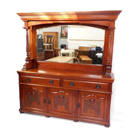 A Victorian mahogany mirror back sideboard, the outswept pediment with egg and dart moulding, the back inset with bevelled glass, raised on fluted and turned Ionic column supports over two long drawers above three carved panelled doors, raised on bun feet