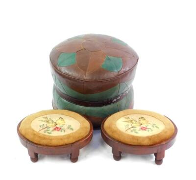 A brown and green leatherette circular pouffe, with a brown belt decoration, 44cm diameter, together with a pair of oval stained beech foot stools, wool work decorated with birds, raised on turned feet. (3)
