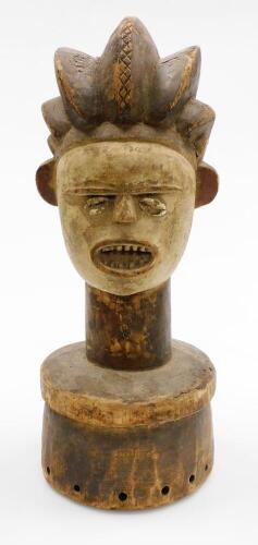 An African tribal hardwood head figure, with elongated features, shell eyes and open mouth, on a circular part pierced base, 45cm high.