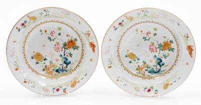 A pair of 18thC Chinese porcelain soup bowls, decorated with stork standing on a fence beside flowers, predominantly in pink, green and orange, with a decorative outer border of geese birds and flowers, 23cm diameter. (AF)