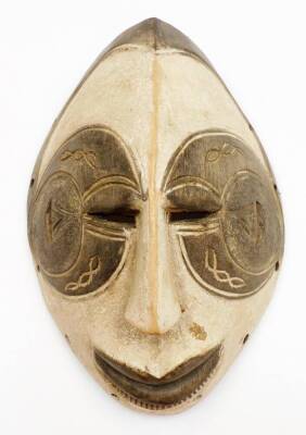 An African tribal face mask, of shaped ellipse form with pierced eyes, partially carved face and an arrangement of circular holes to the border, 31cm high.