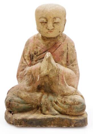 A Chinese carved wood statue of a monk, in flowing robes, at prayer in seated pose, possibly 18thC, 23cm high.