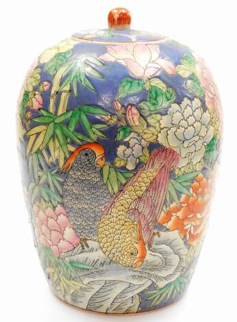 A Chinese famille rose ovoid jar and cover decorated with parakeets and chrysanthemums, bamboo etc on a blue ground, printed six character Qianlong mark to base, 20thC, 34cm high.