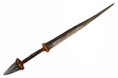 An African tribal knife, with tapering blade, turned handle with metal arrowhead pommel, 68cm wide.