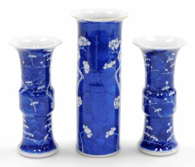 A Chinese porcelain prunus vase trio, comprising two gu shaped vases and a cylinder vase of trumpet form, decorated with prunus flowers on a blue ground, four character Kangxi marks to base of two,19thC, 19cm high. - 4