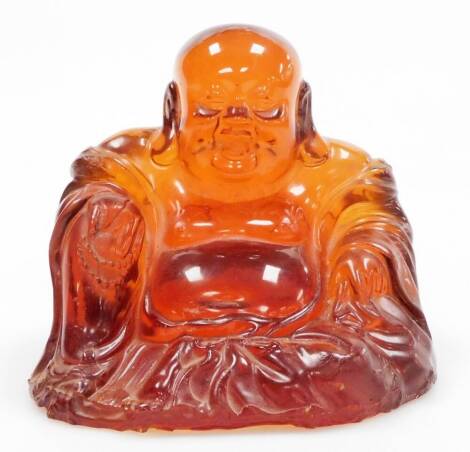 An amber coloured resin figure of Buddha, in seated pose wearing flowing robes, 13cm high.