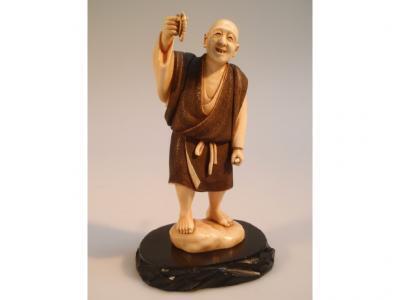 A Japanese ivory Okimono figure of a man smiling and holding up a crayfish