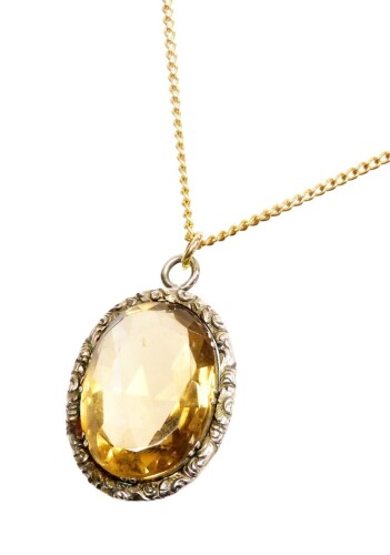 A silver framed citrine pendant and chain, the oval pendant in a florally engraved oval silver frame, 3cm x 2.5cm, on a gold plated chain.