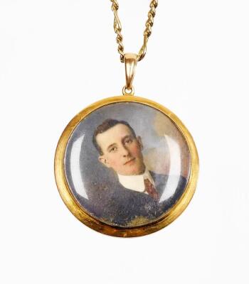 A Victorian portrait pendant and chain, the circular portrait depicting a gentleman in suit, unsigned, in a yellow metal frame bearing the initials AHL?, marked 10ct, 4cm diameter, on a gold plated chain.