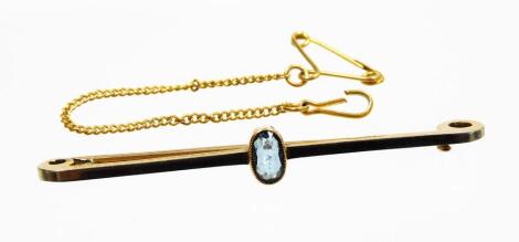 An aquamarine set bar brooch, with central oval aquamarine, in rub over setting, on a white coloured plain pin, with gold coloured sides and back, with safety chain, marked 15ct, 5cm wide, 3.2g all in.