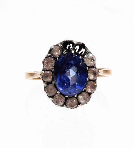 An Edwardian style dress ring, with synthetic sapphire and paste stones arranged in a floral cluster, size M, two white paste stones lacking, on a yellow metal band, unmarked, 3g all in.