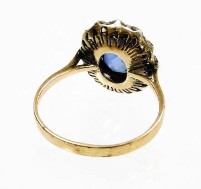 An Edwardian style dress ring, with synthetic sapphire and paste stones arranged in a floral cluster, size M, two white paste stones lacking, on a yellow metal band, unmarked, 3g all in. - 2