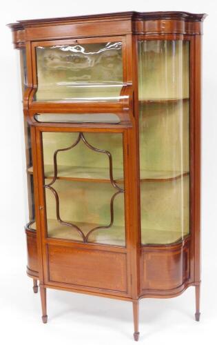 An unusual Edwardian mahogany serpentine and box wood display cabinet, with curved glass fall door to the upper compartment, flanked by further curved glass sections, above an astragal glazed floral section with lower panel, on square taper legs terminati