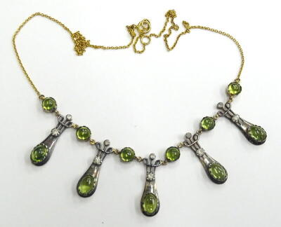 An Art Nouveau style polished peridot and diamond necklace, set with five oval polished peridots and six circular stones, with tiny diamonds, in white metal setting, on a yellow metal chain, marked 375, 45cm long overall, boxed.