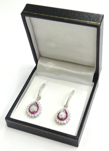 A pair of diamond and ruby drop earrings, each set with central rose cut diamond approx 1.23cts, surrounded by calibre cut rubies 1.37cts overall, with round brilliant cut diamonds totalling 1.49cts, and diamond set hoop drops, white metal, unmarked, 7.6g