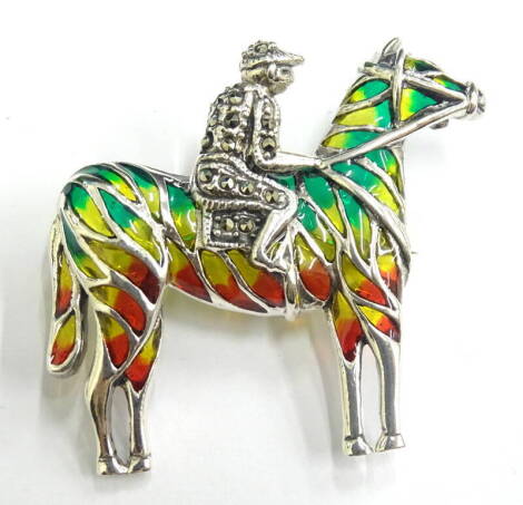 A plique-a-jour jockey brooch, with design of horse and jockey, set with marcasite and red, green and yellow colouring, white metal marked 925, 3cm wide.