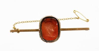 A 9ct gold carnelian set bar brooch, with rectangular cut orange intaglio depicting a gentleman in quarter profile, in a yellow metal fanned design backing, on a later plain pin, with safety chain, 6.5cm wide, 7.3g all in.