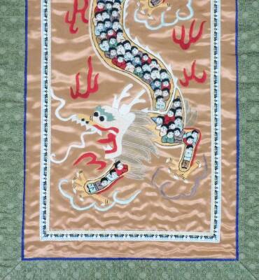 A 20thC Chinese silk embroidery panel depicting a dragon among clouds, the body composed of children. 84cm x 32cm. - 3