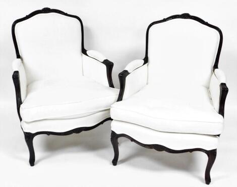 A pair of French style armed chairs, with scroll fluted carved fames, and cabriole legs, upholstered to match the previous lot.