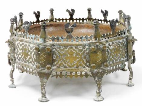 A Tibetan style octagonal brass stand, with raised gallery burlier of cockerels within finials, with two ring handles, on stylized feet and incorporating a shallow iron dish, 32cm deep, 19cm high.